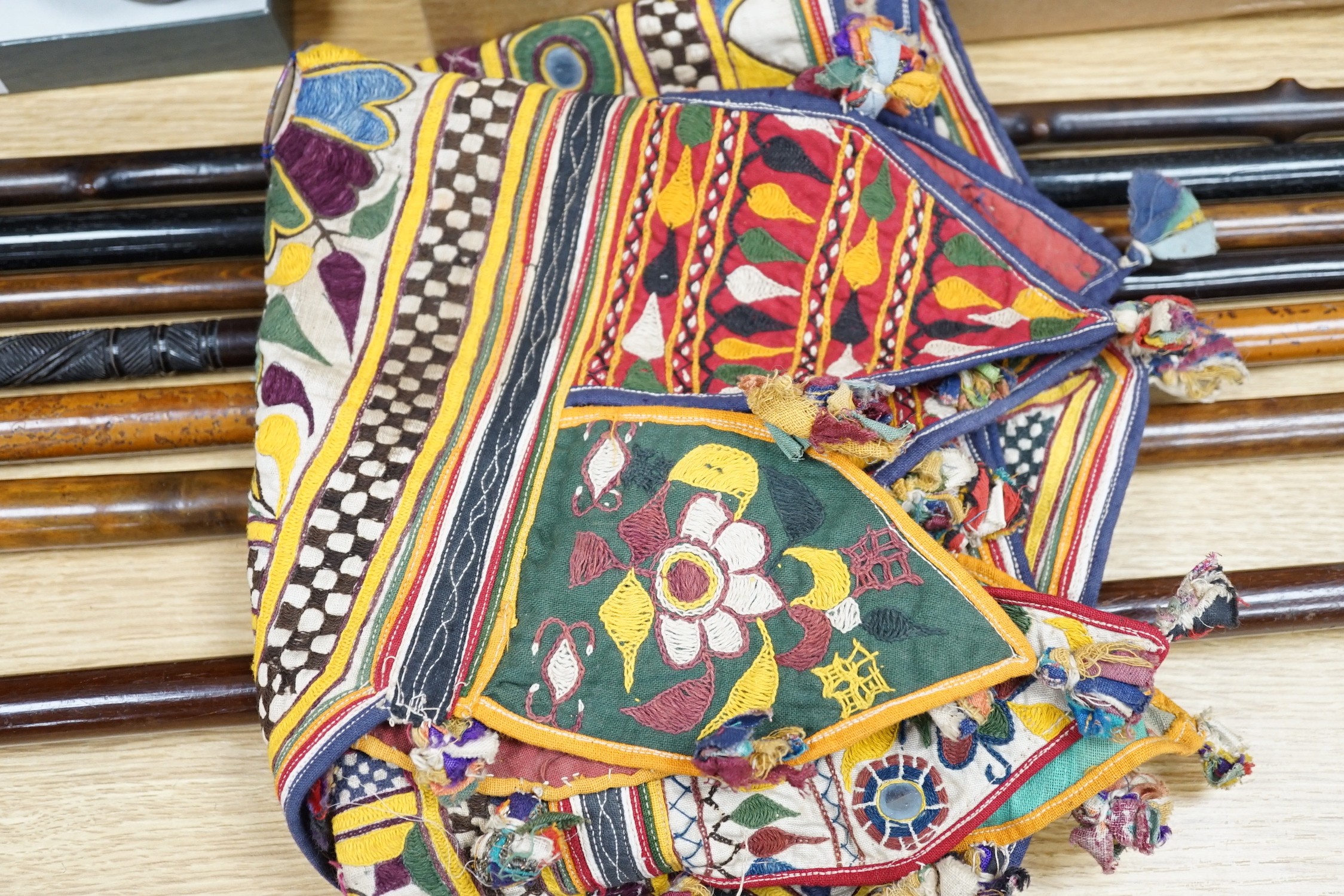 A collection of Indian mirrored worked hangings, a length of batik fabric and a woven shawl